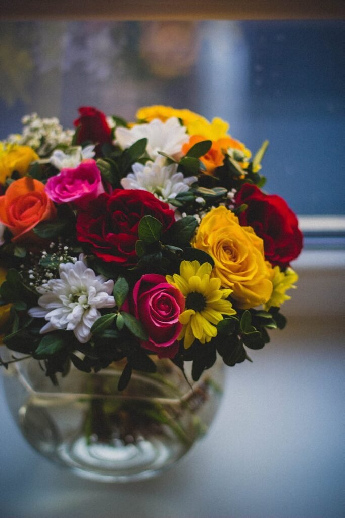 A colorful bouquet of roses and daisies in a glass vase on a windowsill, capturing the essence of spring.